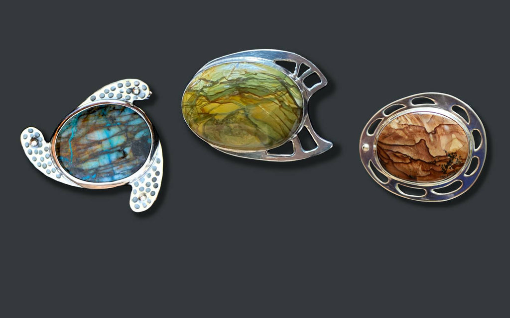 Three dramatic silver belt buckles featuring colorful stones: green and brown jasper and blue chrysocolla.