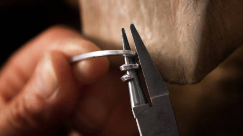 Close-up shot of metal-working, with hand, silver wire and pliers.