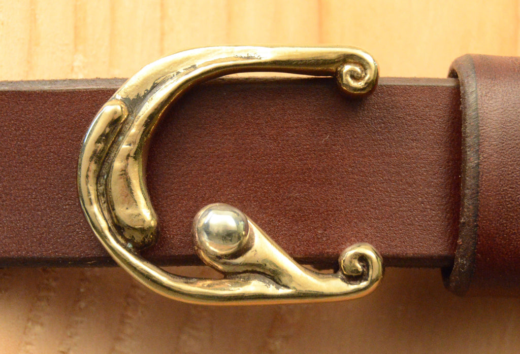 Bronze, hand-cast belt buckle displayed with brown leather belt. 