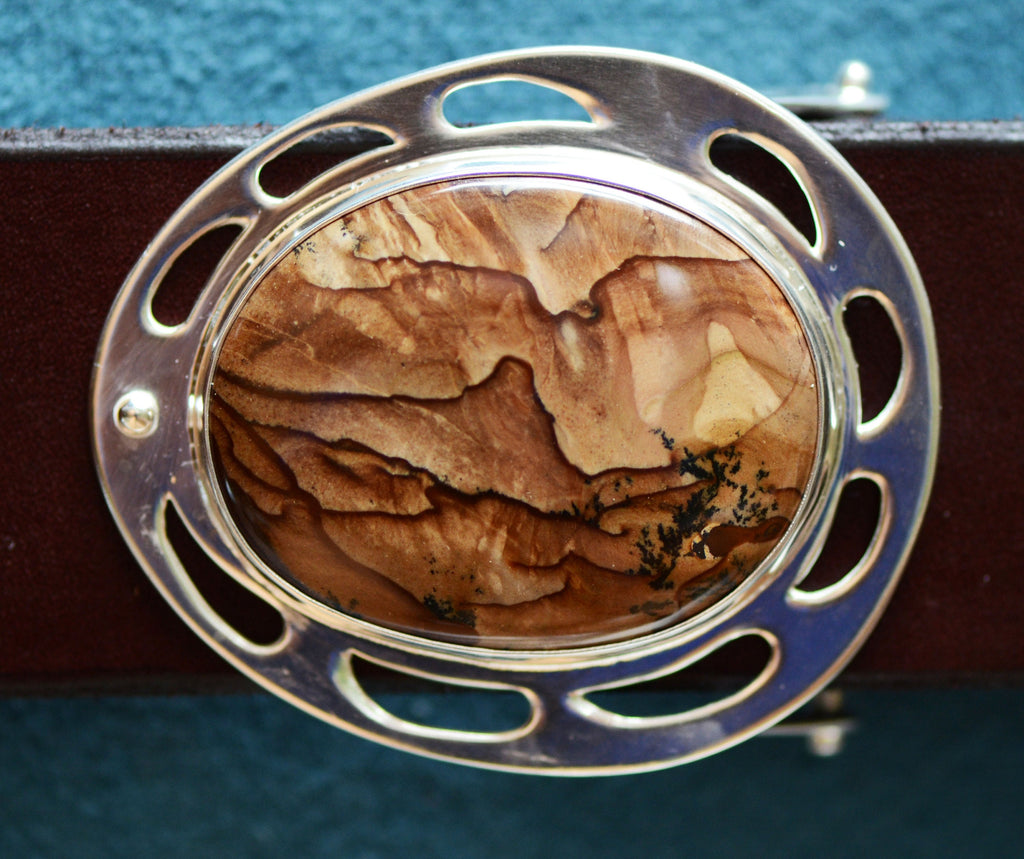 Close-up of Deschutes Jasper Sterling Silver Belt Buckle, dramatic brown stone with dark figuring cut in an oval shape, in a sterling silver setting. Shown with a hand-made brown leather belt. 