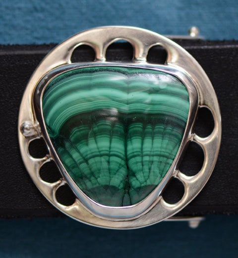 close-up of dramatically-patterned green and black amachite cabochon stone in a silver belt buckle  setting